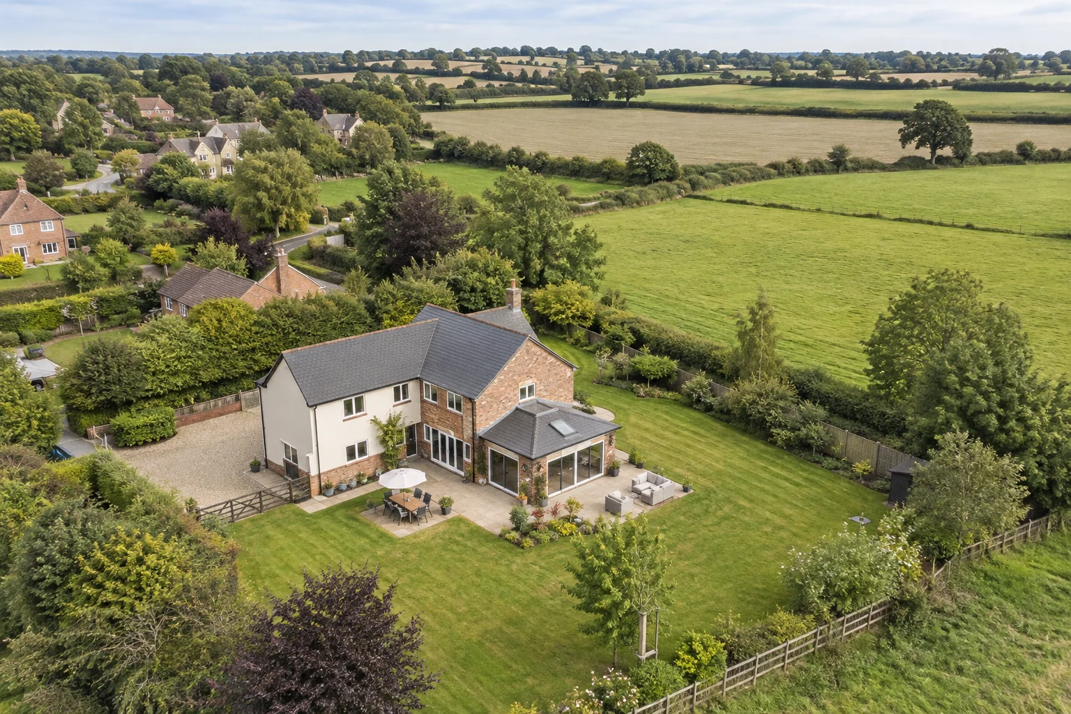 Aerial view of a detached house, garden and surrounding fields